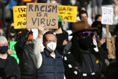 A man holds a sign that reads "Racism is a Virus" during the "We Are Not Silent" rally against anti-Asian hate in response to recent anti-Asian crime in the Chinatown-International District of Seattle earlier this month.