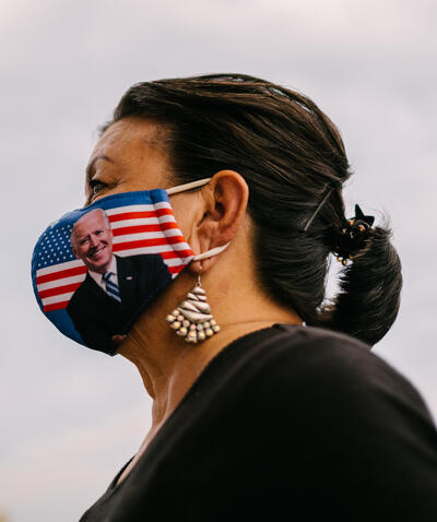 A Latina woman wears a face mask with presidential candidate Joe Biden on it.